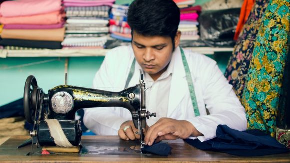 A young man uses a sewing machine.