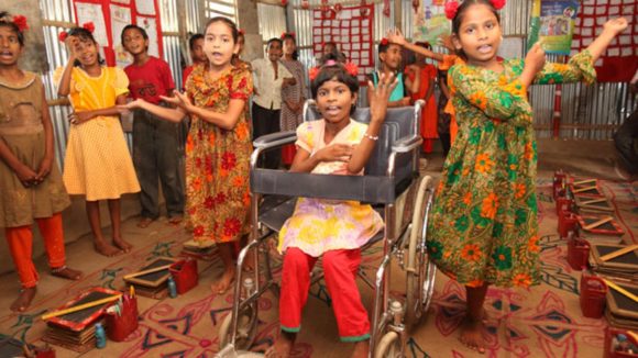 A group of girls are dancing. One of them is in a wheelchair.