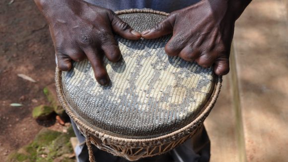 Close up of hands on a drum. The person is missing the fingers on their left hand.