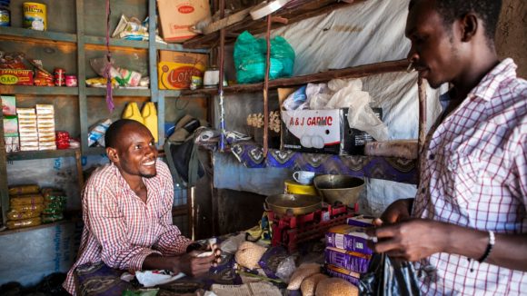 A shop owner serves a customer in his small shop in Kenya.