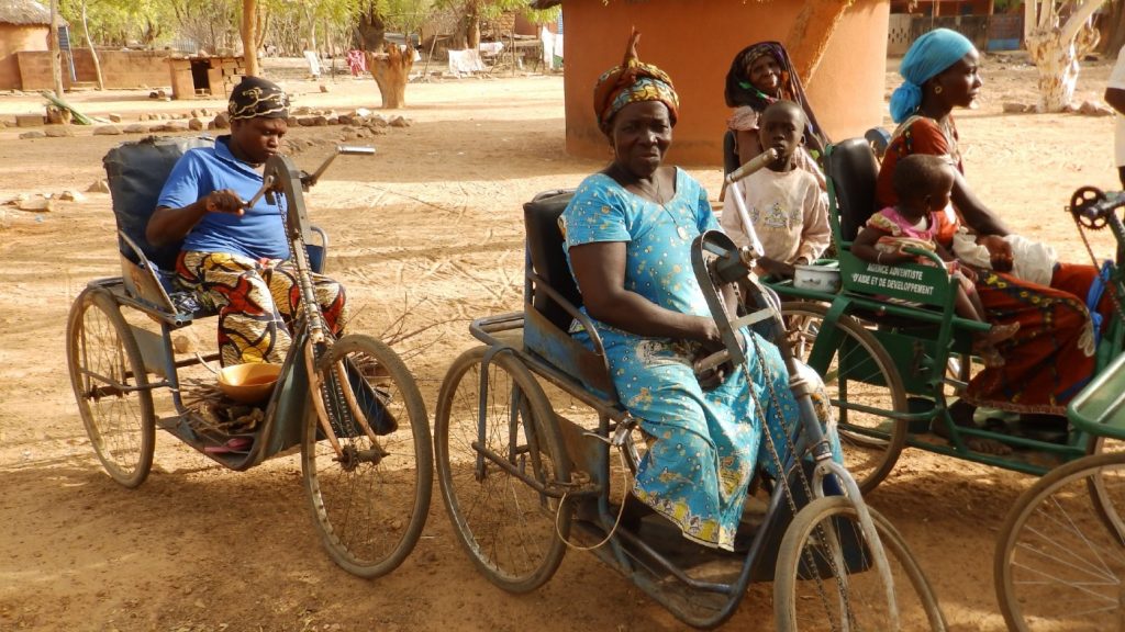 A group of women use adapted bicycles with seats to get around.