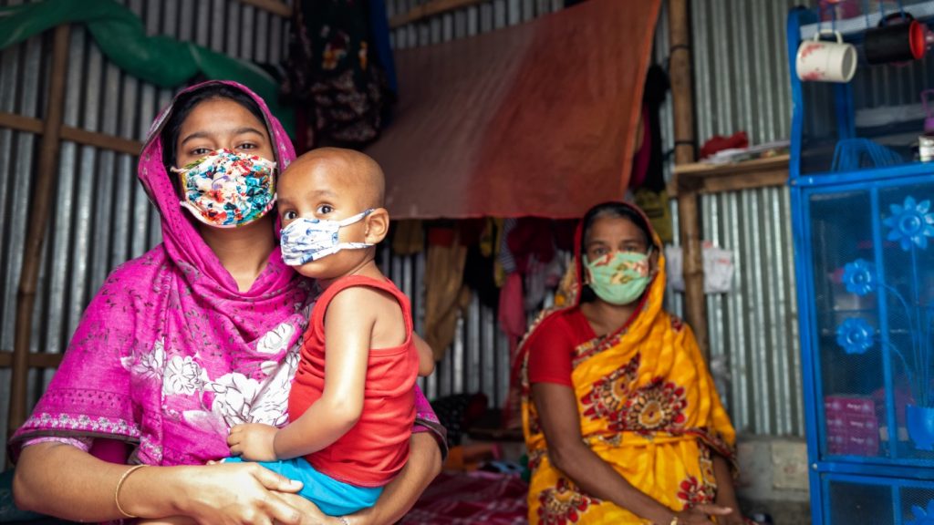 Two women and a baby wear face masks in a house in Bangladesh.