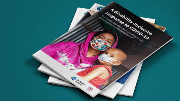 A pile of three reports. The top one is entitled: A disability-inclusive response to COVID-19 - four lessons learned about including people with disabilities in humanitarian aid. The image shows a mother holding a child, both wearing facemasks. The cover includes an Inclusive Futures and UK aid logo.