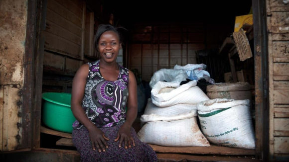 A women entrepeneur smiling next to bags of grain.