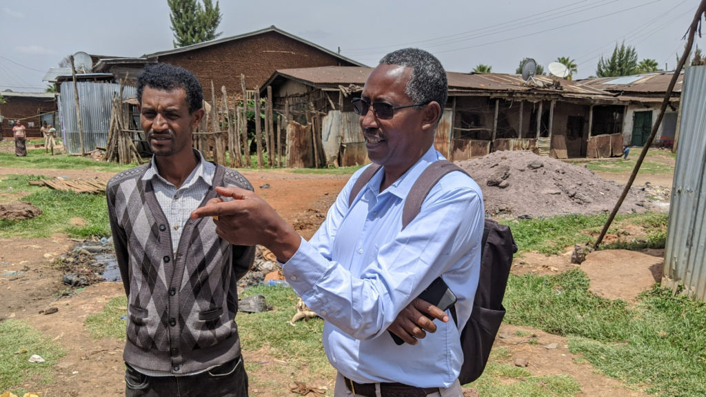 A LINC staff member talks to a man in a rural village.