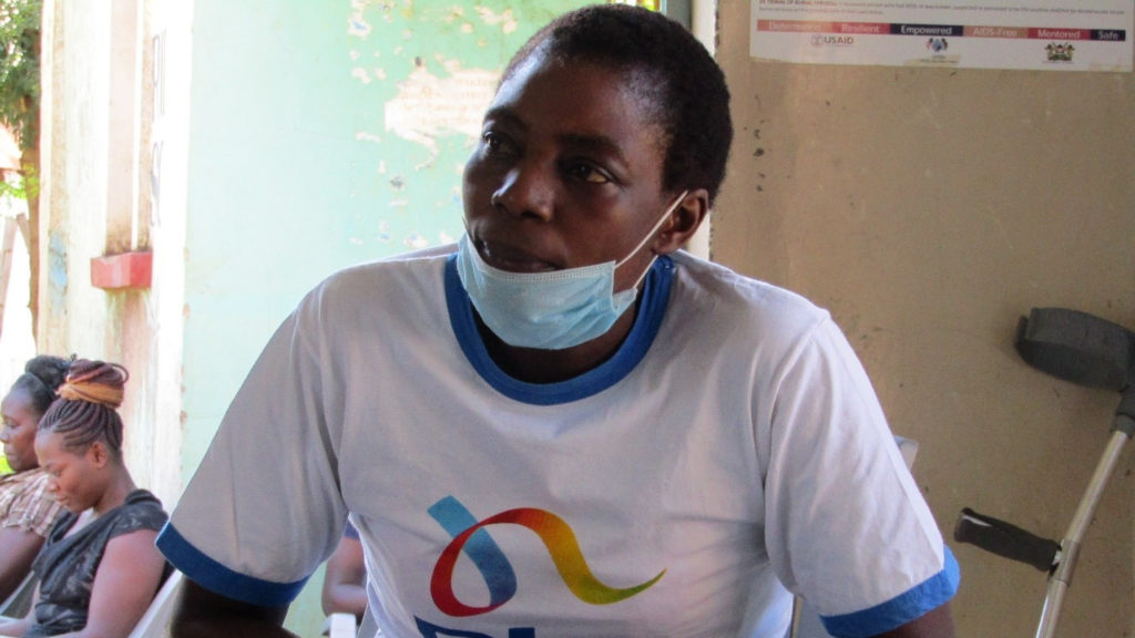 A head and shoulders picture of a woman wearing a face mask, with crutches by her side