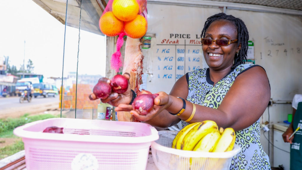 Erinah Susan has a visual impairment. She is working at her stall and is counting onions in her hands.