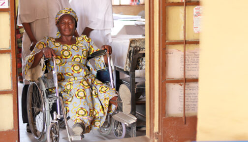 A woman in a wheelchair waiting in the doorway of a health centre in Nigeria.