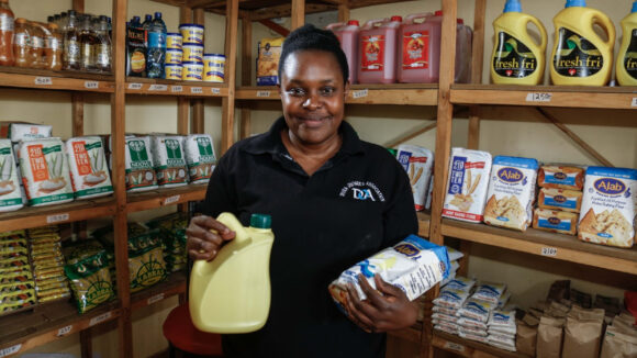 A woman wearing a black T-shirt is holding items that she sells in her shop.