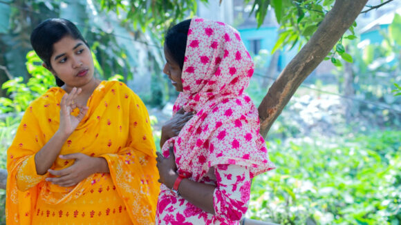 A woman and girl with colourful headscarfs are communicating with sign language.
