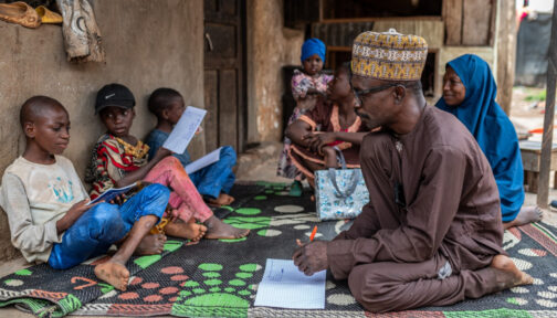 A family sit crossed legged outside their home in northern Nigeria.