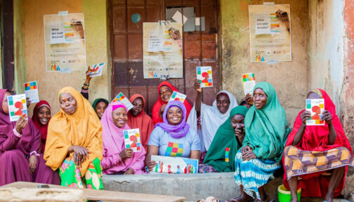 Women with disabilities in Nigeria in colourful headdresses smile for the camera during a peer-to-peer workshop.