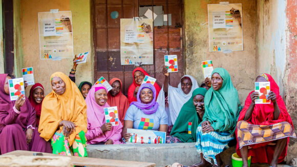 Women with disabilities in Nigeria in colourful headdresses smile for the camera during a peer-to-peer workshop.