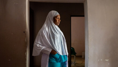 A nurse in Nigeria stands with her hands in her pockets outside a family planning unit.