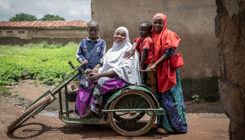 A woman using a mobility scooter is surrounded by her three children.
